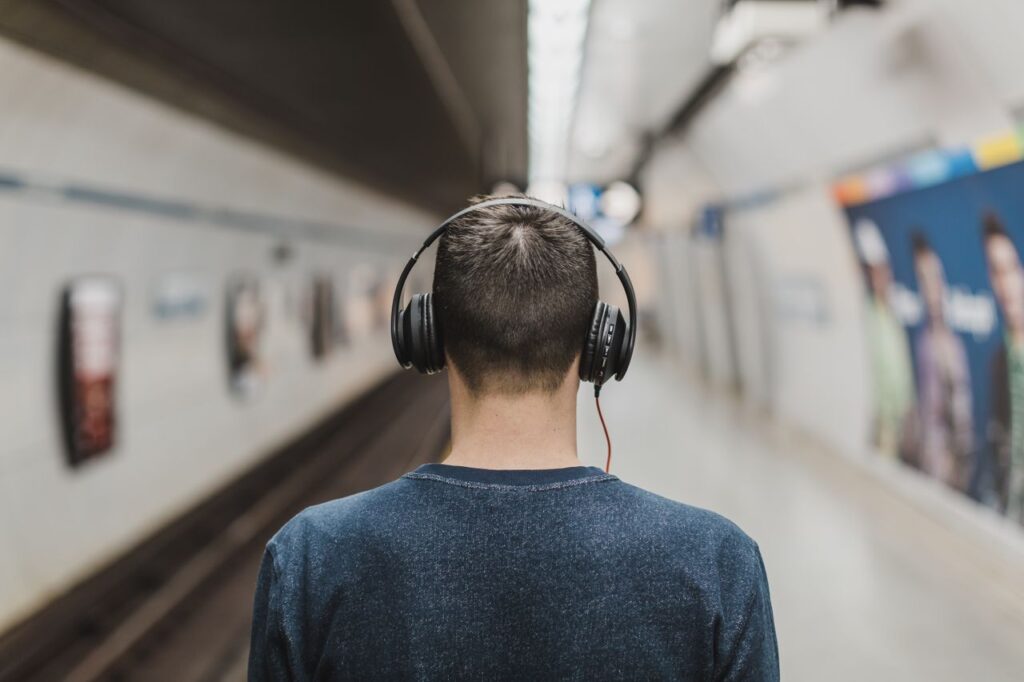Mand med store høretelefoner venter på en metrostation
