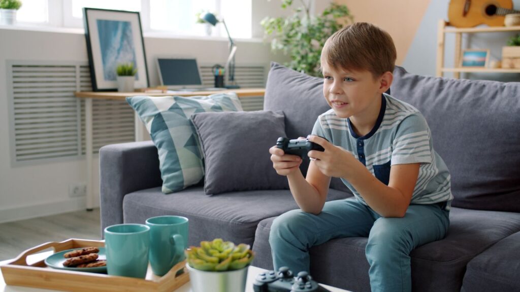 Dreng sidder i en sofa og spiller med en controller