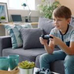 Dreng sidder i en sofa og spiller med en controller